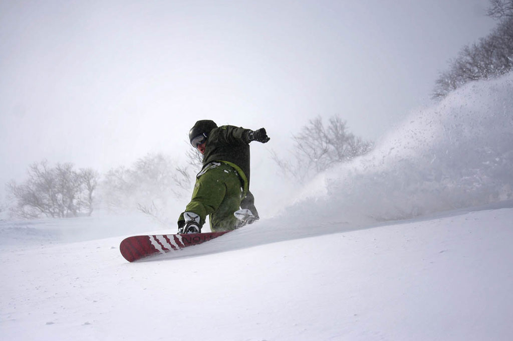 Man snowboarding down mountain in Niseko, Japan